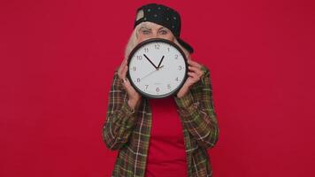 Senior woman holding clock watch, hiding, checking time on clock running late to work being in delay video
