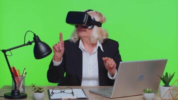 Senior businesswoman using headset helmet app to play simulation game watching virtual reality video