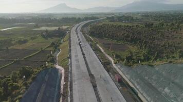 Aerial View of a Majestic Road Stretching through Expansive Green Fields and Mountains video