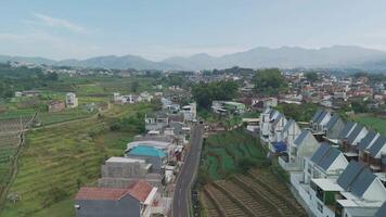 Aerial View of Serene Agricultural Landscape with Modern Houses and Majestic Mountains in the Background video