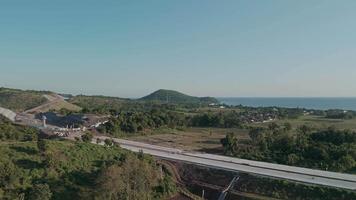 Aerial Landscape Overlooking Developing Highway Surrounded by Lush Greenery and Coastal Views video