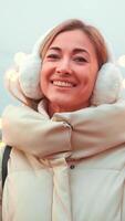 Smiling Woman in a Warm Coat and Earmuffs Enjoying Winter Festivities at Christmas video