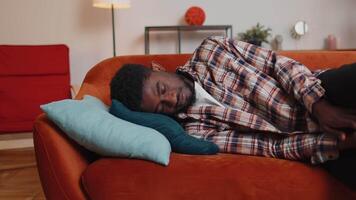 Overworked african american man falling asleep on sofa after party, lack of energy, breakdown video
