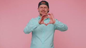 Smiling man makes heart gesture demonstrates love sign expresses good feelings and sympathy video