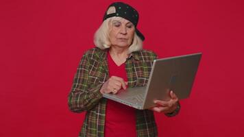 Happy senior woman typing on laptop computer, working on project, enjoying results, winning lottery video