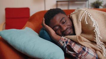 African american young man sleeping quietly in bedroom at home, smiling, lying on comfortable bed video