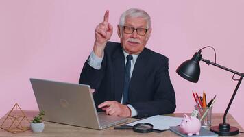 Senior businessman smiling pointing to camera, choosing lucky winner, indicating to awesome you video