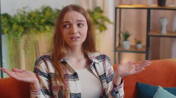 Pretty girl alone at home having doubts, no idea, being clueless and uncertain shrugs shoulders video