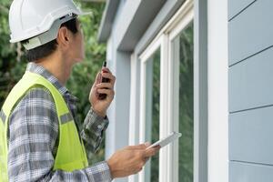 inspector inspecting construction and quality assurance new house using a checklist. Engineers or architects or contactor work to build the house before handing it over to the homeowner photo