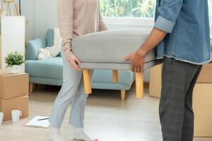 Moving house, relocation. Couple help set sofa and move furniture for new apartment, inside the room was a cardboard box contain personal belongings. move in the new condominium photo