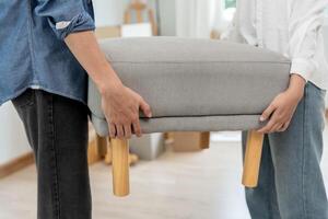 Moving house, relocation. Couple help set sofa and move furniture for new apartment, inside the room was a cardboard box contain personal belongings. move in the new apartment photo