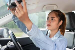 woman adjust car rearview mirror before drive, drives with intent, safe drive, driving practice, cheerful woman sits comfortably in the driver seat with confidently , readiness for a journey photo