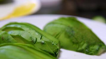 Cut green avocado into slices. Concept of chef in kitchen. video