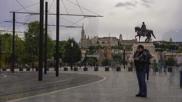 Timelapse showing pedestrians moving near an equestrian statue with Buda Castle in the background. Tram lines and urban elements are visible. video