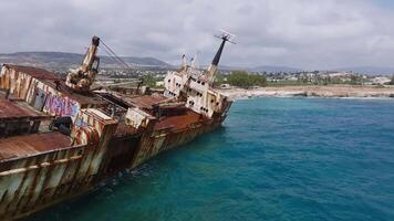 Aerial footage of the Edro III Shipwreck in Cyprus, showing turquoise waters, rugged cliffs, a coastal village, and smooth drone motion over the scene. video