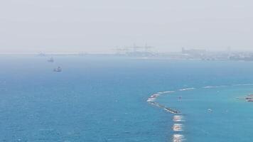 Aerial view of Limassol, Cyprus, showing the coastline, modern buildings, breakwaters, a skyscraper, a port with cranes, and the Mediterranean Sea. video