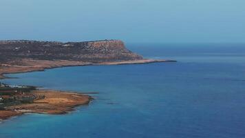 Aerial view of Ayia Napa, Cyprus, showing turquoise waters, rocky shores, whitewashed resorts, and rolling hills as the camera moves along the coast. video