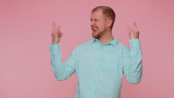 Overjoyed happy man showing rock n roll gesture by hands, cool sign, shouting yeah with crazy face. video