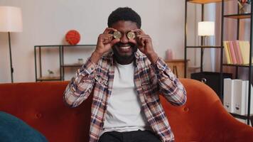 Man freelancer holding two gold coins BTC at home, successful developer programmer stock trader. video