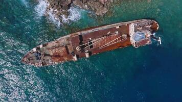 Aerial view of the Edro III shipwreck near Cyprus' rocky coast. The camera moves slowly, showcasing the rusted ship and vibrant blue waters. video