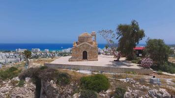 Aerial view of St. Elias Church in Ayia Napa, Cyprus, with gradual circling motion, showing stone architecture, lush greenery, and the Mediterranean Sea. video