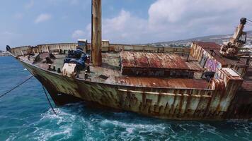 Aerial view of the Edro III shipwreck near Cyprus' rocky coast. Rusted hull, chains, cliffs, and gentle waves create a dynamic coastal scene. video
