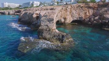 Aerial view of the Love Arch in Ayia Napa, Cyprus, with turquoise waters and waves crashing against rugged cliffs. Camera moves to show various angles. video