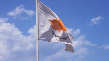The Cyprus flag waves dynamically in the wind, showcasing its orange map and olive branches on a sunny day with scattered clouds. video