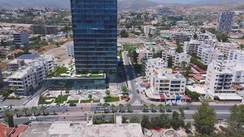 Aerial view of Limassol, Cyprus showing modern buildings, a main road with moving vehicles, and rolling hills in the background. video