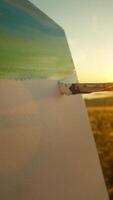 Close-up view of canvas, on which the artist is creating paintbrush painting of blue sky at sunset, with the rays of the setting sun illuminating the natural landscape. video