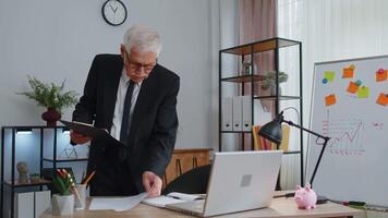 Senior business man examining graphs, analyzing, managing finance documents report at home office. video