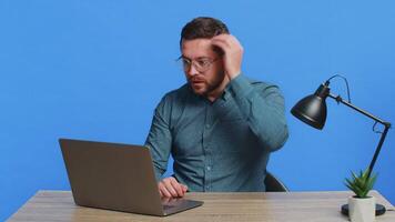 Man using laptop surprised by bad news, fortune loss, game fail, lottery results sitting at table video
