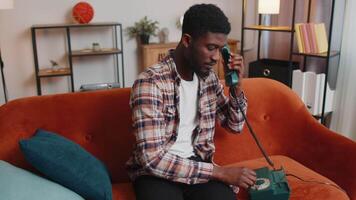 Young adult african american man enjoying talking on retro phone conversation with friend at home video