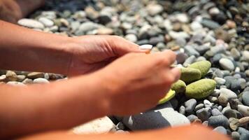 Rocks Hands Beach. Person stacks rocks, on a pebble beach, during daytime, for calming and artistic expression. video