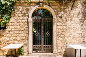 Iron gate set in stone wall under arched doorway. Mediterranean courtyard, vintage architecture and sunny outdoor charm. photo