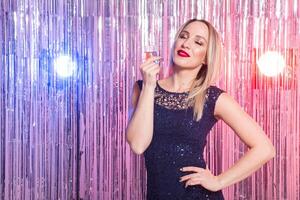 Happy smiling woman in evening dress with glass of sparkling wine over shiny background. photo