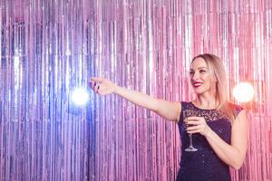 Party, drinks, holidays and celebration concept. Woman in evening dress with glass of sparkling wine over shiny background. photo