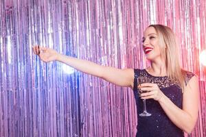Party, drinks, holidays and celebration concept. Smiling woman in evening dress with glass of sparkling wine over shiny background. photo