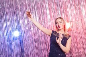 Party, drinks, holidays and celebration concept - woman in evening dress with glass of sparkling wine over shiny background. photo