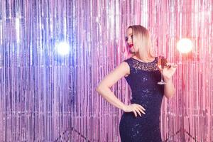 Party, drinks, holidays concept - smiling woman in evening dress with glass of sparkling wine over shiny background. photo