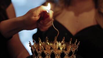 Lighting candle on crown-shaped birthday cake. Close-up of a hand using a lighter to ignite a decorative candle placed on a crown-themed cake during an elegant video