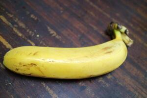 One big ripe a yellow banana is placed on a wooden table photo