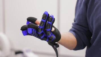 Man wearing advanced robotic exoskeleton glove. Close-up of a person testing a high-tech robotic glove designed for rehabilitation, VR interaction, or enhanced video