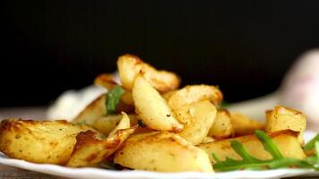Golden potatoes with a crispy crust and spices on a black background video
