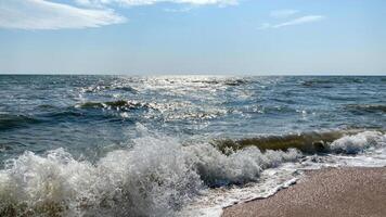 Dynamic close-up view of ocean waves crashing onto the sandy beach under a bright sun photo