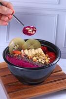 a bowl of purple smoothie with fruit and nuts photo