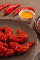 a plate of wings on a table with a bowl of sauce photo