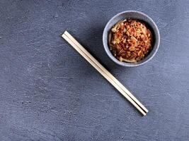 chopsticks and bowl of food on a gray surface photo