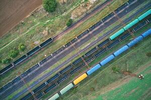 Aerial drone view of a freight train at a railway station, showcasing industrial transport infrastructure with steel tracks and cargo carriages. photo