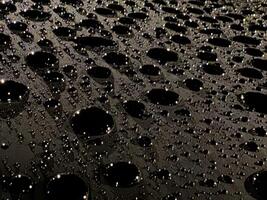 Close Up of Water Droplets on Dark Surface photo